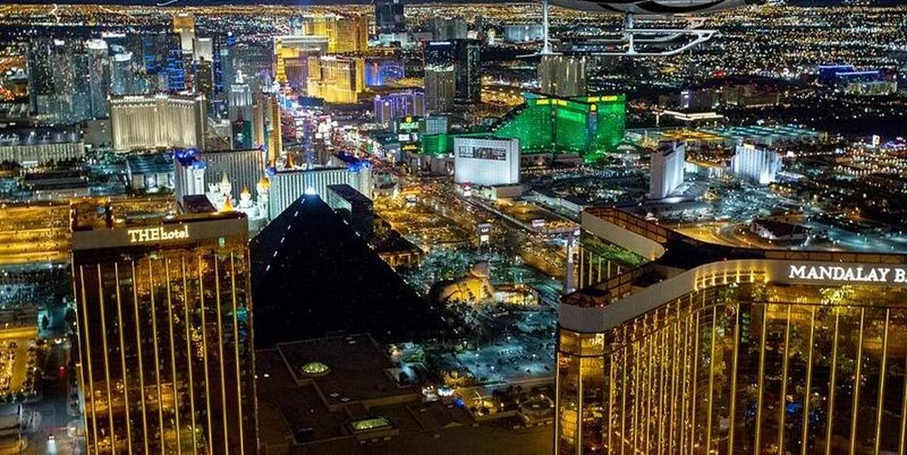 The Las Vegas Strip from the air after dark: the black pyramid of the Luxor, the gold towers of Mandalay Bay and four miles of lit boulevard running north