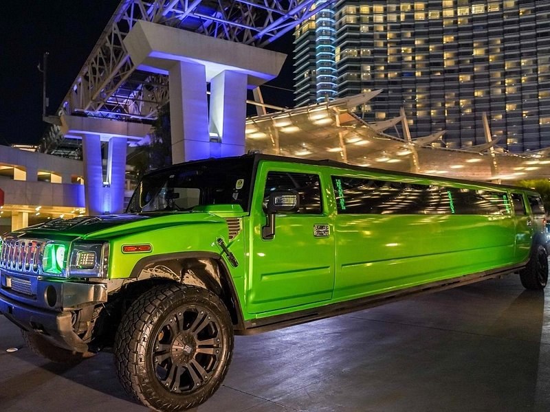 A lime-green stretch limousine parked at night outside a lit resort on the Las Vegas Strip