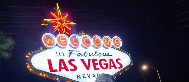 The Welcome to Fabulous Las Vegas sign lit after dark, its yellow star and bulb border burning against a black sky